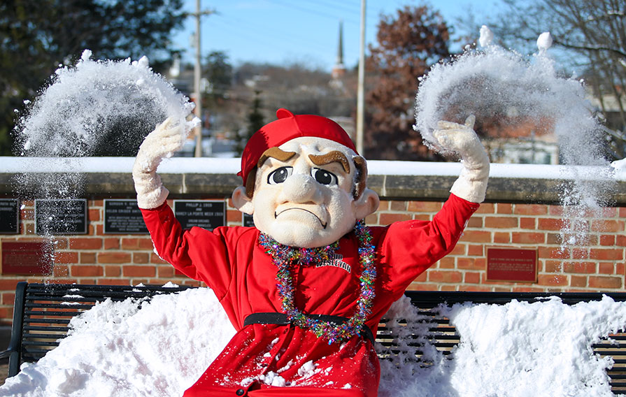 Bishop Mascot Sitting on Bench Playing with Snow